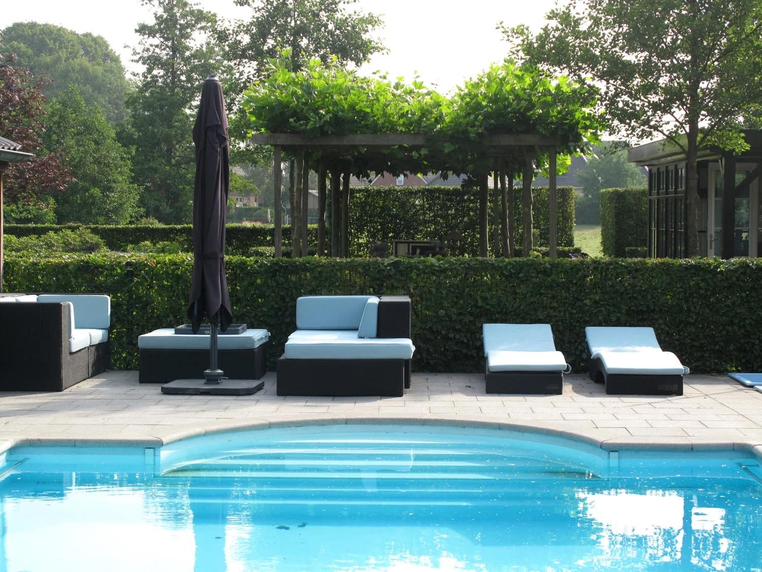 Diabolo: Loungeset aan zwembad | Het Buitenland Tuin en Landschap (tuinontwerp Nijmegen, tuinarchitect Nijmegen) Loungeset aan zwembad en pergola met dakplatanen erachter