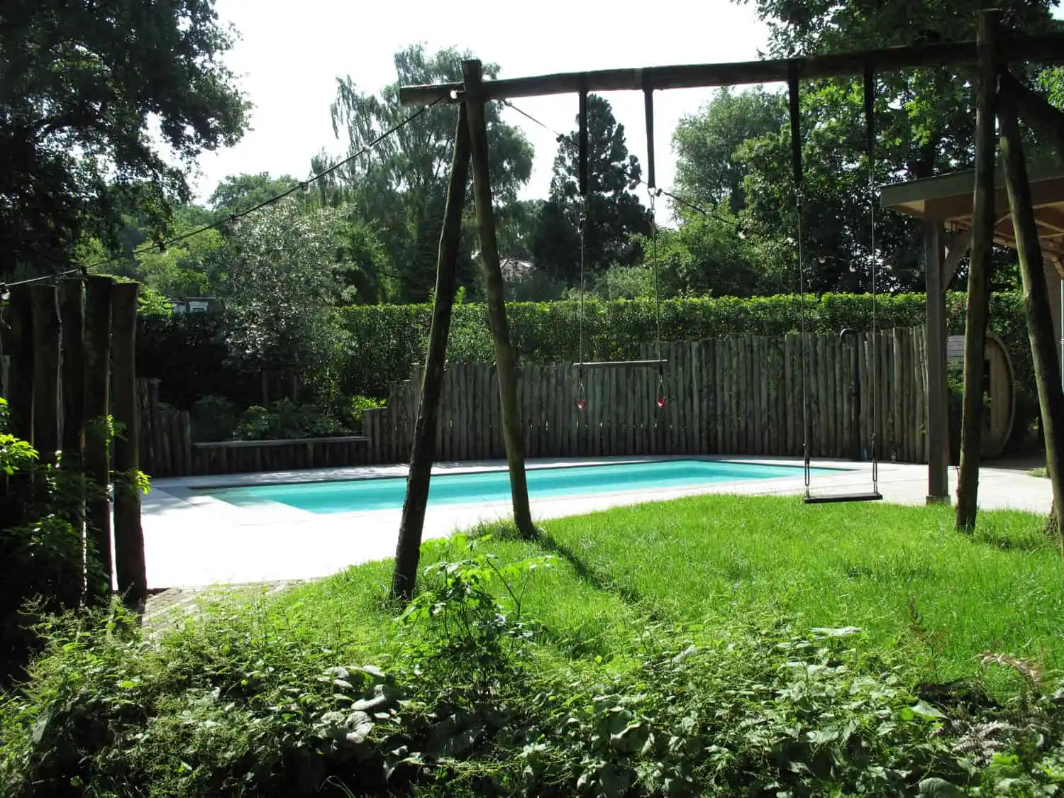 Zwemburcht: Doorkijkje onder schommel | Het Buitenland Tuin en Landschap (zwembadtuin, tuinontwerp Nijmegen, tuinarchitect Nijmegen) Doorkijkje onder dubbele schommel in gazon naar zwembad